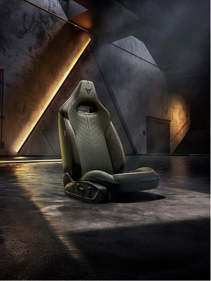 CUPRA Performance-Sitz freigestellt in einer dunklen Industriekulisse mit warmen Lichtreflexen auf dem Boden