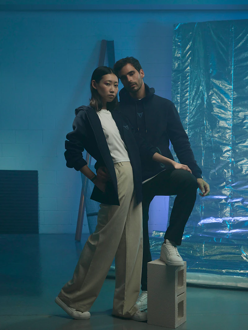 Zwei Personen in CUPRA Collection Kleidung, Hoodie in Dunkelblau mit CUPRA Logo